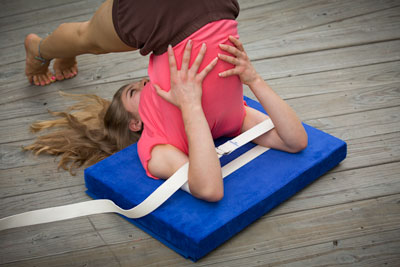 girl doing halasana using belt around arms